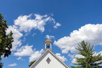 Bell tower of the church with a white cross, symbolizing Christianity and religion.