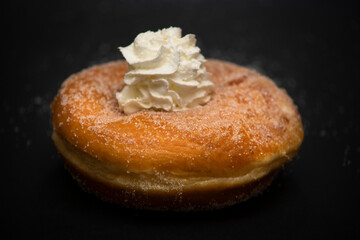 isolated fresh donut in Italian breakfast with sugar and handmade whipped cream in the middle on black background