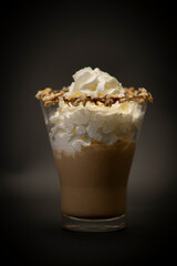 Tasty Italian hot chocolate in a big glass. Is a tasty chocolate with handmade whipped crema on top, is a n Italian ice cream with chocolate in a large fancy glass. All with a black background