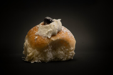 isolated fresh fried donut in Italian breakfast with sugar and handmade whipped cream in the middle and tasty chocolate on black background