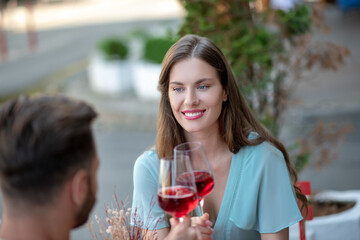 Bearded male and female sitting in open air cafe, drinking wine