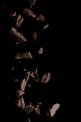 Falling pieces of chocolate on a black background, frozen in motion
