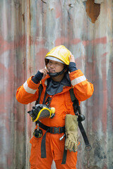 Obraz na płótnie Canvas The portrait of Asian firefighters are wearing orange fire protection uniform mask and helmet front of building.