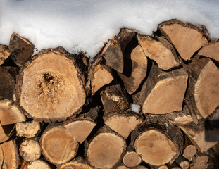 Snow on top of a pile of chopped firewood
