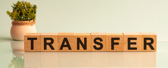 Transfer message word on a wooden desk on cube blocks with a flower on background