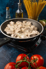 Fresh pork meat in a pan fried on a background of vegetables