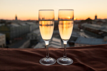 Two glasses of champagne on the background of city roofs at sunset