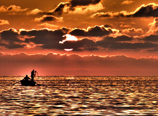 Silhouettes of fishermen at red sunset.