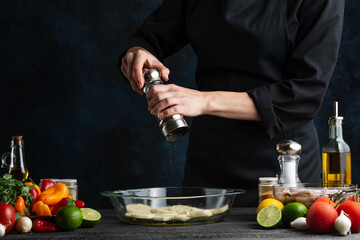 Chef peppers potatoes for baking, on the background of vegetables, freezing in motion