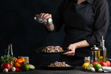 The chef prepares a dish of potatoes with octopus sprinkling with salt, freezing in motion, cooking seafood dishes, gastronomy and cooking, recipe book