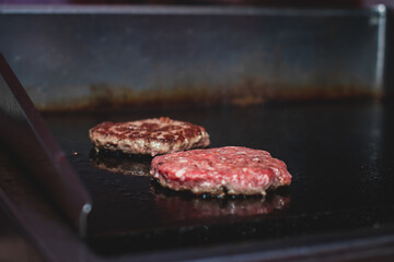Process of cooking classic burgers with beef on open-air, view of chef hands in  gloves with variety of fillings and ingredients on wooden desk and stove