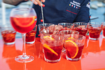 View of alcohol setting on catering banquet table, row line of red colored aperitif alcohol cocktails on a party, negroni and spritz, vodka, and others on decorated catering bouquet table event