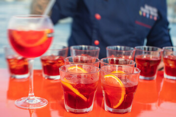 View of alcohol setting on catering banquet table, row line of red colored aperitif alcohol cocktails on a party, negroni and spritz, vodka, and others on decorated catering bouquet table event