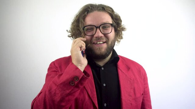 Successful young businessman with a beard in a red suit talking on the phone. A benevolent smile, laughter.On white background.4k