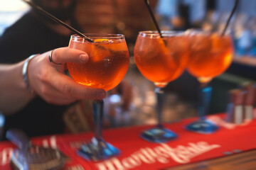 Row line of red colored negroni and spritz aperitif alcohol cocktails on a party of alcohol setting on catering banquet table, vodka, and others on decorated catering table event with bartender