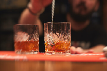 Row line of red colored negroni and spritz aperitif alcohol cocktails on a party of alcohol setting on catering banquet table, vodka, and others on decorated catering table event with bartender