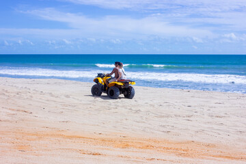Fototapeta na wymiar Young couple riding an ATV on Brazil beach