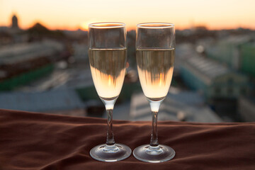 Two glasses of champagne on the background of city roofs at sunset
