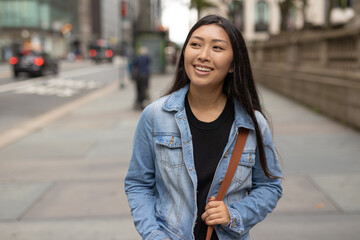 Young Asian woman walking city street smiling happy