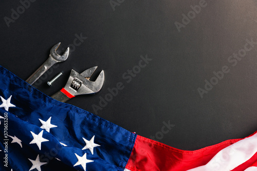 Labor day concept, Top view flat lay of different kinds wrenches with American flag on black. First Monday in September, creation of labor movement and dedicated to social of the American worker