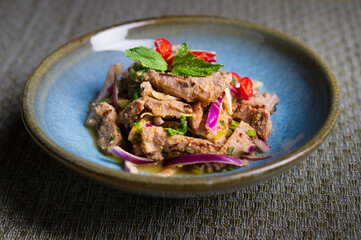 thai or vietnam style sweet and sour sliced grilled pork salad with onions, mint, red chili