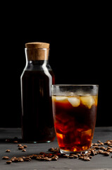 Glass and jar of filter coffee on a dark board