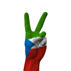 Hand making victory sign, equatorial guinea painted with flag as symbol of victory, win, success - isolated on white background