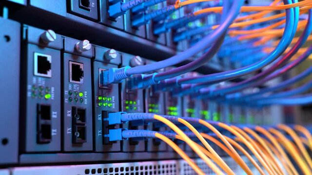man working in network server room with fiber optic hub for digital communications and internet