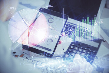 Double exposure of man's hands holding and using a digital device and forex graph drawing. Financial market concept.