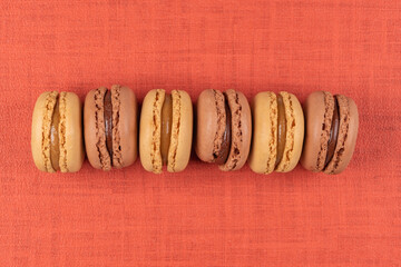 Six coffee and chocolated flavoured macaroons on vinyl background