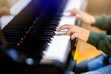 Fototapeta na wymiar Selective focus to kid fingers and piano key to play the piano. There are musical instrument for concert or learning music. Close up hand of child musician playing the piano on stage.