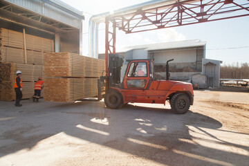 workers load boards with an industrial loader at a sawmill