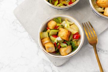 Tofu and Vegetables Stir Fry in Blue and White Bowls on White Background