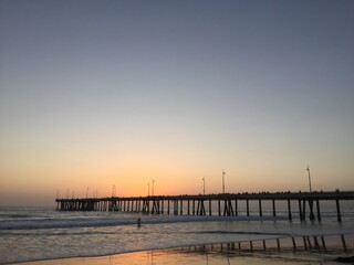 Fototapeta na wymiar Landscape view of pier over sandy beach shore at sunset