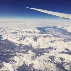Naklejka na ściany i meble Aerial view of snow mountain terrain from airplane window