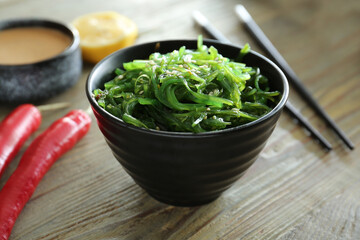 Bowl with tasty seaweed salad on table