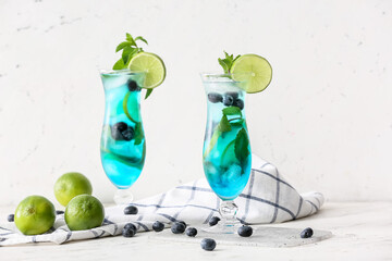 Glasses of tasty blue mojito cocktail on white background