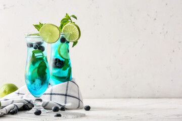Glasses of tasty blue mojito cocktail on white background