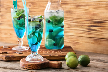 Glass of tasty blue mojito cocktail on wooden background
