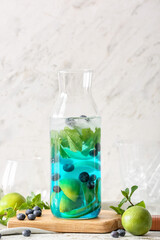 Bottle of tasty blue mojito cocktail on white background