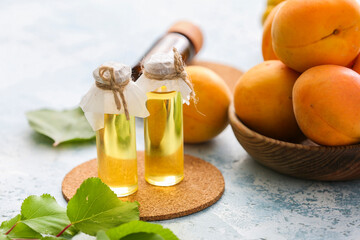 Bottles of apricot essential oil on color background