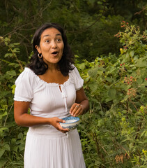 young Hispanic woman surprised while picking blackberries 
