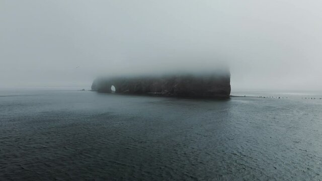 The Famous Perce Rock Formation In The Gaspe Peninsula, Quebec, Canada Covered With Fog - tracking shot