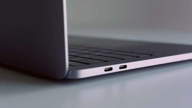 Close up side view of silver laptop on white table. Action. New portable computer details with usb ports, concept of modern technologies.