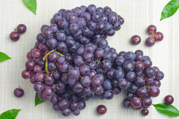 A large bunch of seedless grapes of dark purple lay on a cloth background.