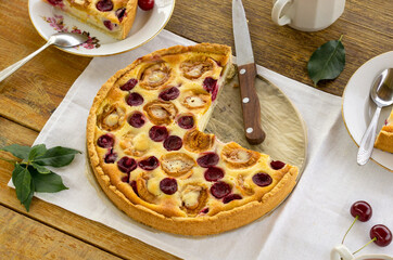 Fruit pie with sour cream filling, apricots and cherries on a wooden table