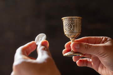 Pray with holding loaf and little cup of the wine.