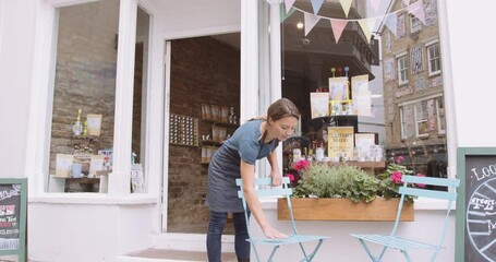 Female retail store owner entrepreneur opening shop and taking out furniture