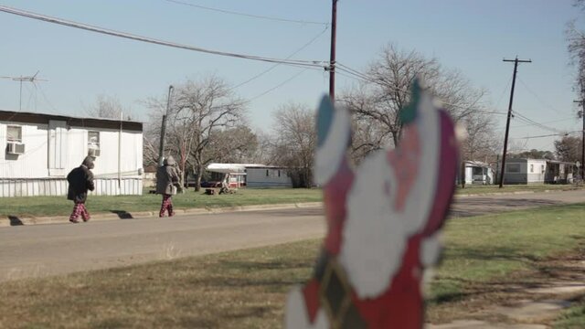 Children walking down the road behind Santa Christmas decoration