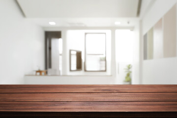 Empty wooden desk space and blurry background of home window for product display montage.
